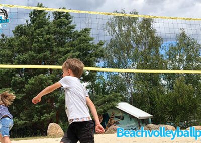 Zwei Kinder spielen auf dem Beachvolleyball-Platz Beachvolleyball