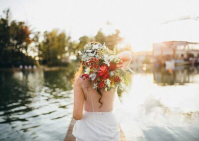 Braut mit Brautkleid steht mit Blumen in der Hand auf dem Steg mitten im Wasser