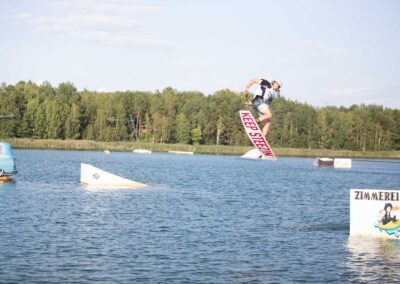 Wakeboarder springt über einen Kicker, der im Wasser schwimmt