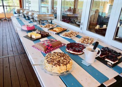 Kuchen in verschiedenen Varianten steht neben dem Buffet einer Feier auf dem Tisch