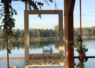 Bilderrahmen für Gäste einer Hochzeitsfeier mit Blick auf den See mit der Wasserski- und Wakeboardanlage