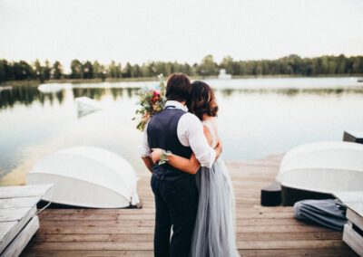 Braut und Bräutigam stehen frisch vermählt am Steg und blicken sich umarmend auf den See