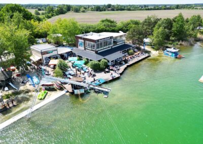 Wassersport Anlage am See mit Restaurant und Imbiss mit großem Sitzbereich mit Loungemöbeln und Sonnenschirmen