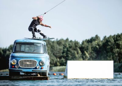 Sportliche Frau slidet auf dem Dach des Barkas Bus, der im Wasser schwimmt