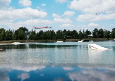Verschiedene Hindernisse für Wassersport stehen im sich spiegelndem See