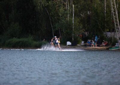Wakeboarder fährt auf dem Wasser und Zuschauer am Ufer sehen zu